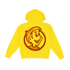A bright yellow hoodie shown from the back, featuring a large circular graphic of a smiling cartoon face made from red tajin powder.