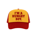 A red and yellow trucker hat with the text 'I'M A HUNGRY BOY.' printed in red on the yellow front panel.